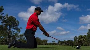 Tiger Woods joga golfe de joelhos