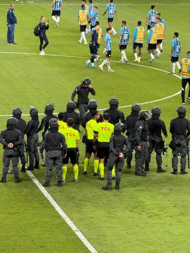 Polícia de choque rodeia a equipa de arbitragem após o Grémio-Internacional
