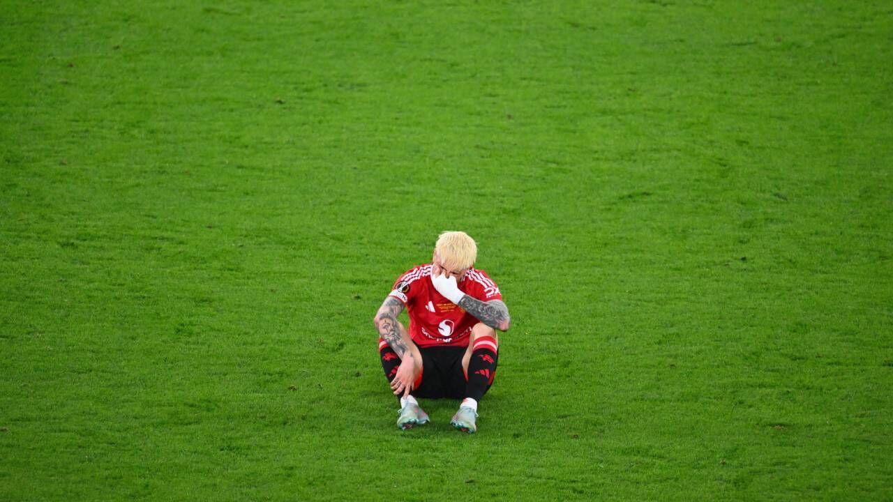 Jogador de futebol parece desolado no relvado após o jogo.
