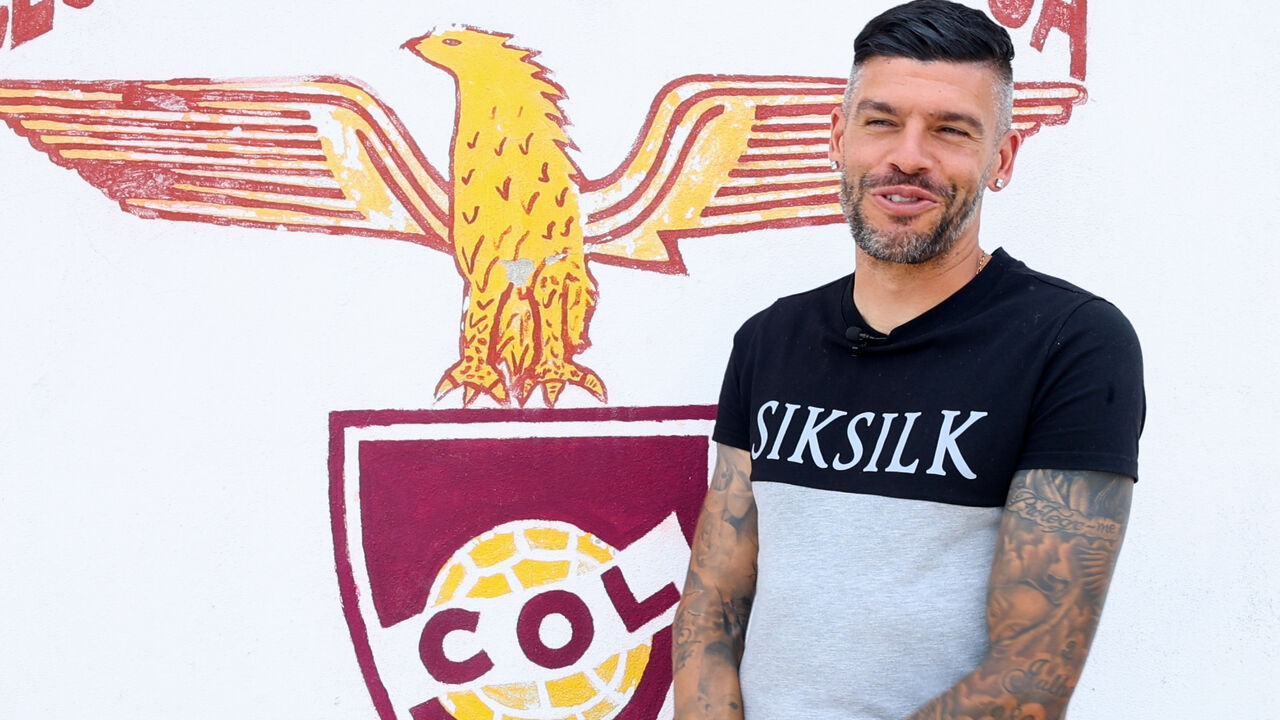 Homem posa junto ao símbolo do clube desportivo Colo-Colo