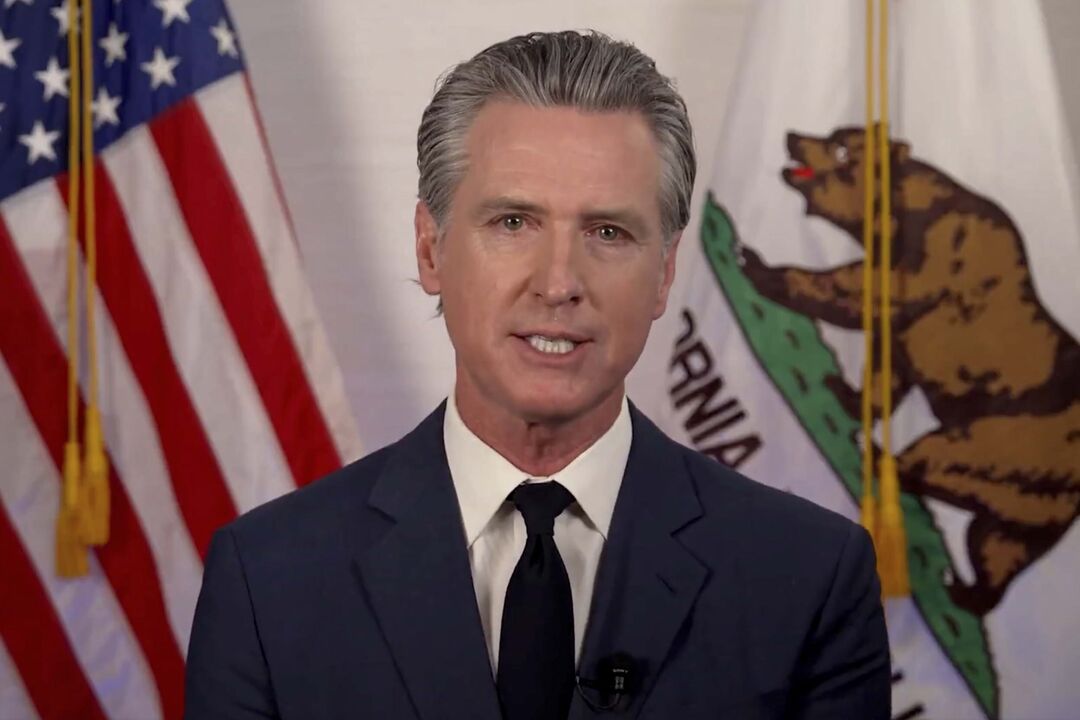 Gavin Newsom discursa com as bandeiras da Califórnia e dos EUA no fundo