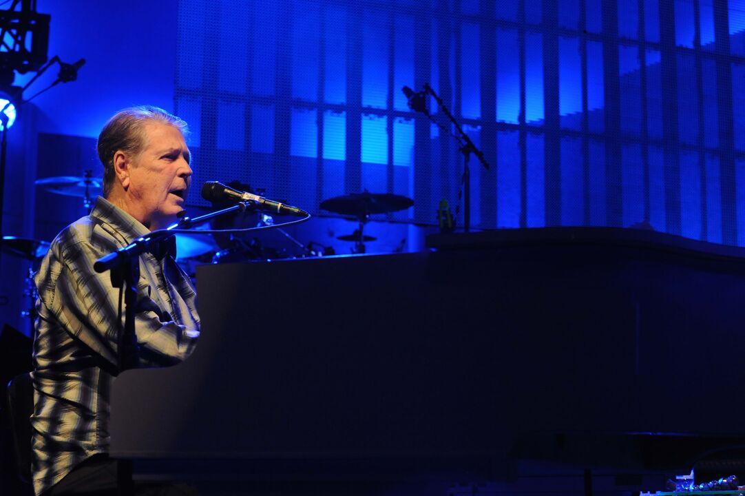 Músico atua ao piano sob luzes azuis, num palco