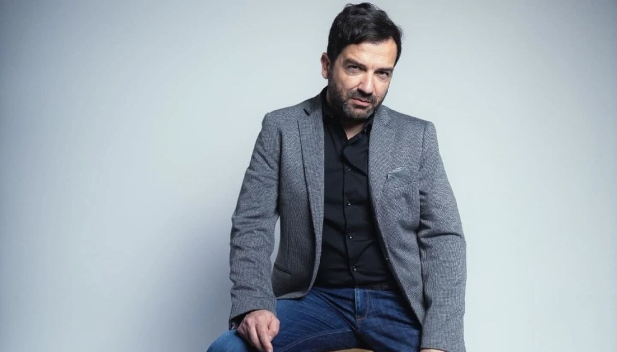 Homem posa com blazer cinza e camisa preta