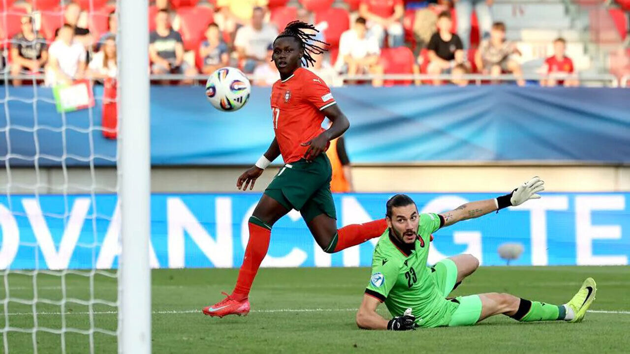 Guarda-redes tenta defender remate de jogador no jogo de futebol