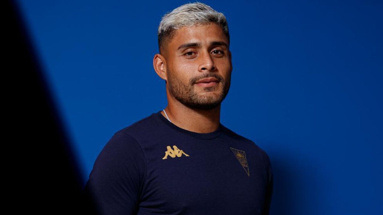 Jogador de futebol posa com a camisola do clube num fundo azul