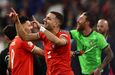 Jogadores celebram vitória em campo com camisolas vermelhas e verdes
