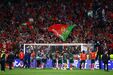 Fãs e jogadores de futebol celebram um golo com a bandeira de Portugal em destaque
