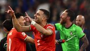 Jogadores celebram vitória em campo com camisolas vermelhas e verdes