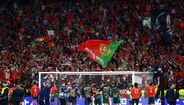 Fãs e jogadores de futebol celebram um golo com a bandeira de Portugal em destaque