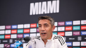 Um homem discursa em Miami, diante de um painel com logótipos