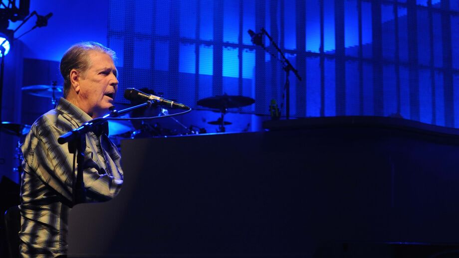 Músico atua ao piano sob luzes azuis, num palco