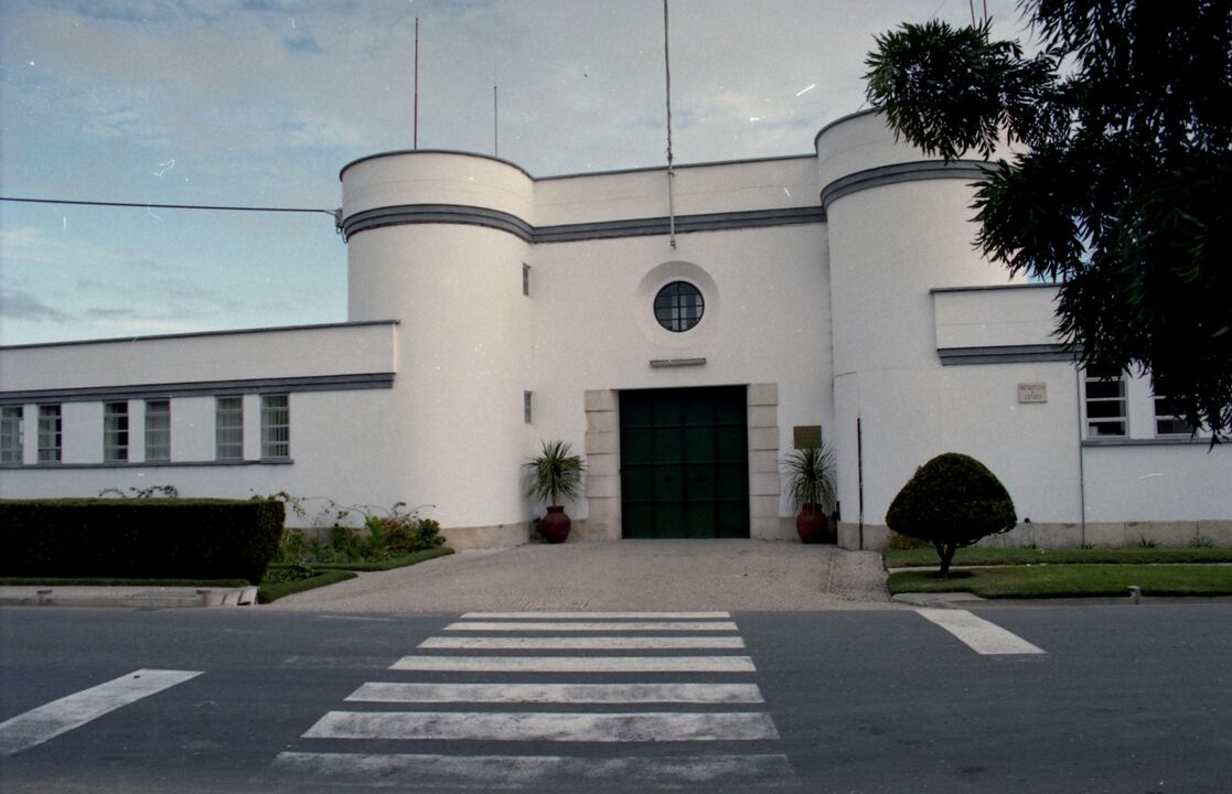 Edifício branco com elementos cilíndricos e porta verde em Lisboa