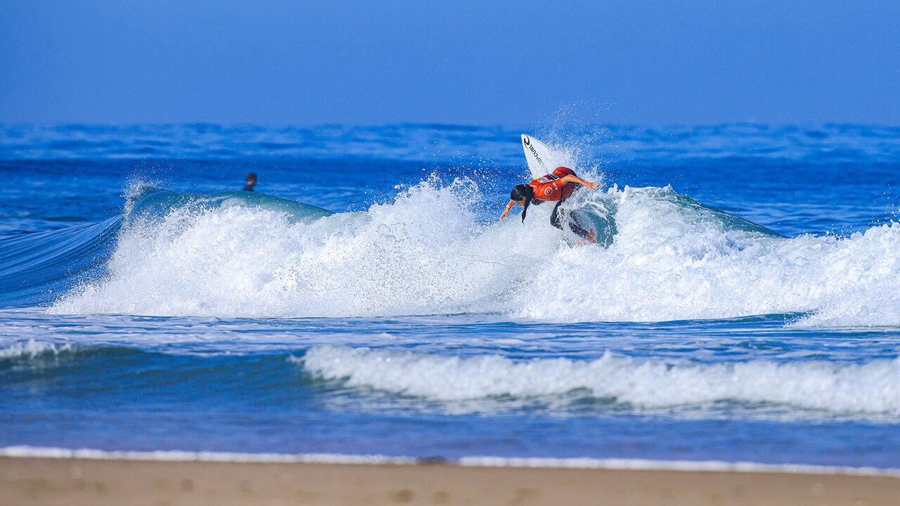 Surfista compete numa onda em dia de sol