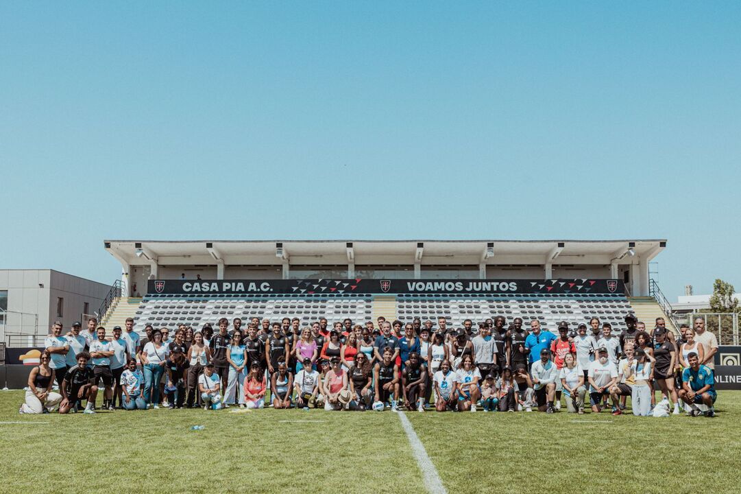 Grupo de pessoas junta-se no campo de futebol do Casa Pia A.C