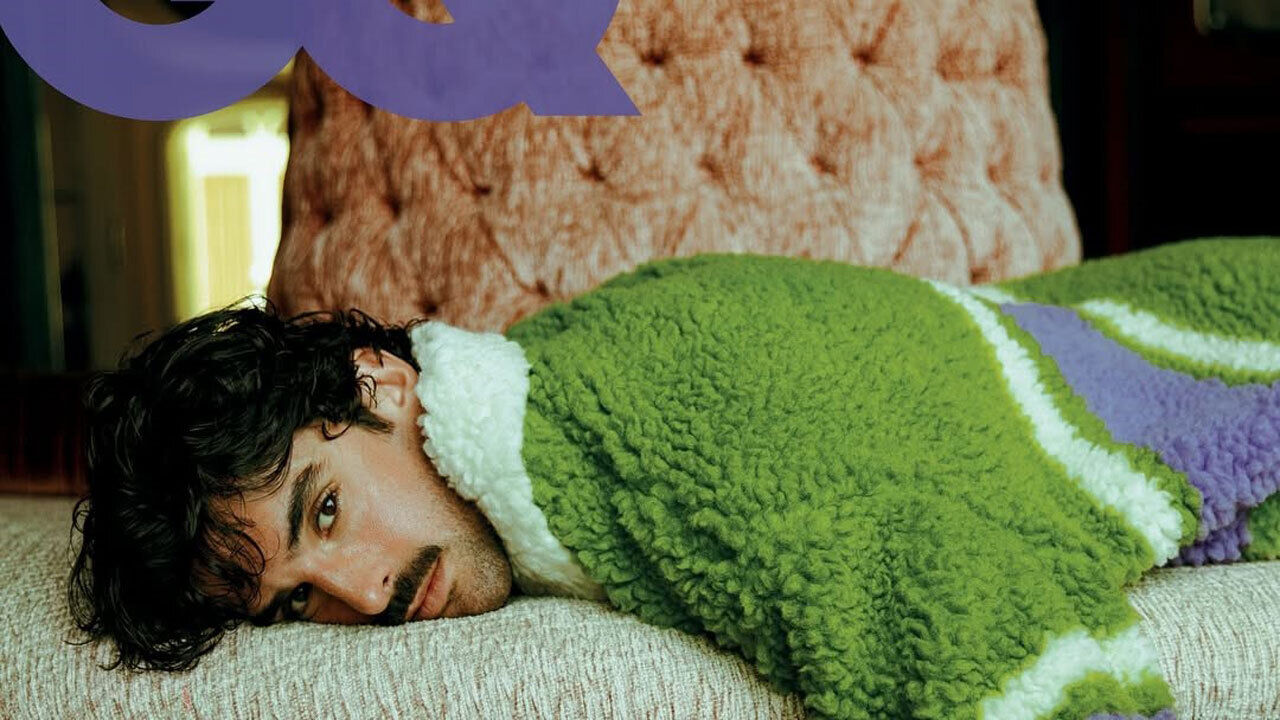 Homem deitado num sofá, com uma camisola verde, numa imagem da GQ