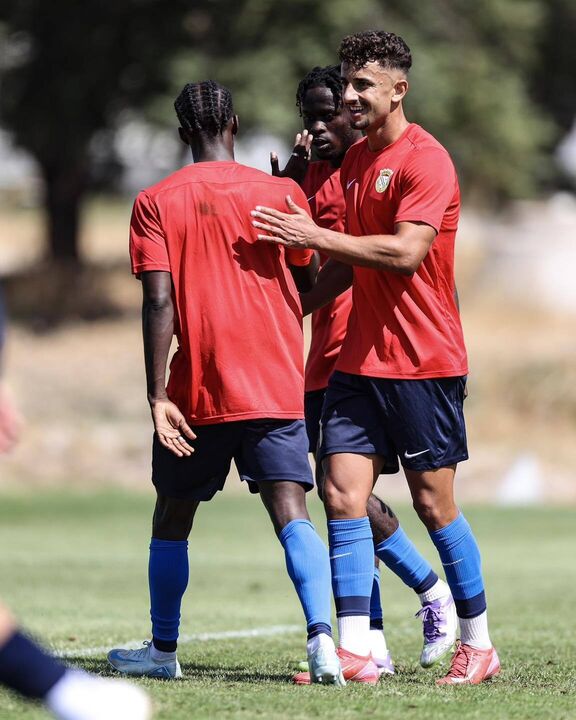 Jogadores de futebol treinam com camisolas vermelhas e calções azuis