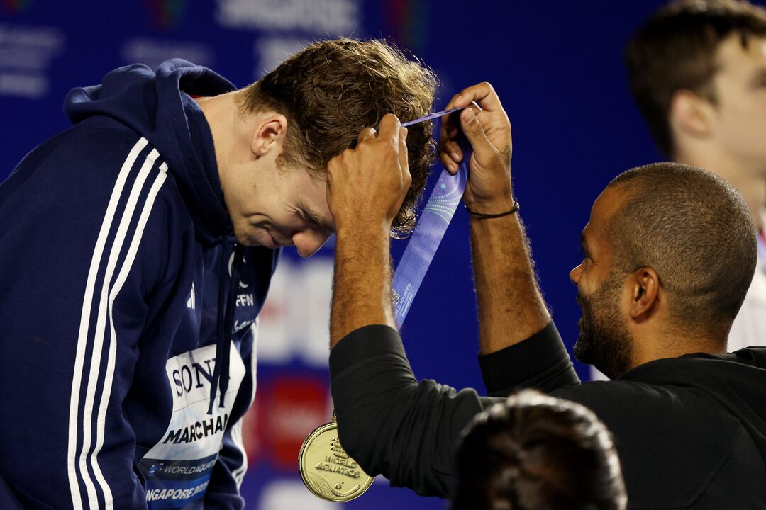 Léon Marchand recebe medalha de ouro das mãos de Tony Parker em Singapura.
