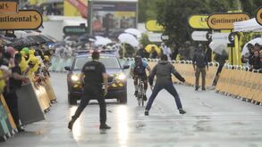 Ciclista compete sob chuva com apoio de carro da polícia e público