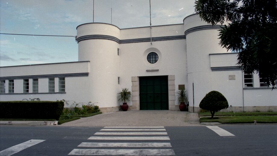 Edifício branco com elementos cilíndricos e porta verde em Lisboa