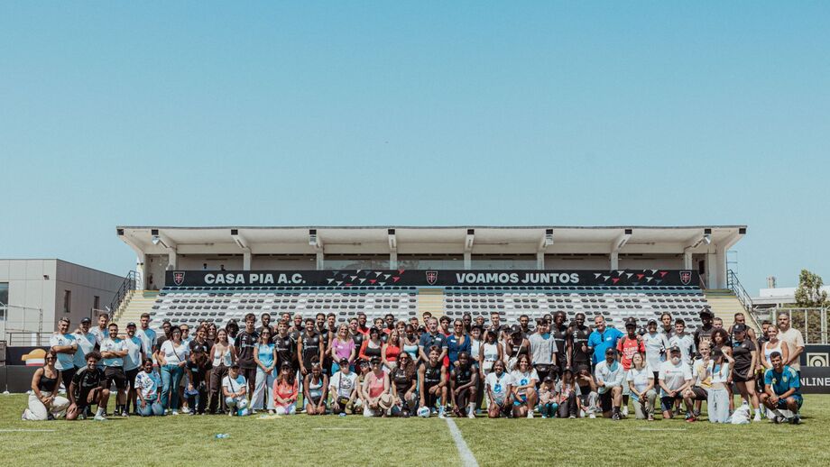 Grupo de pessoas junta-se no campo de futebol do Casa Pia A.C