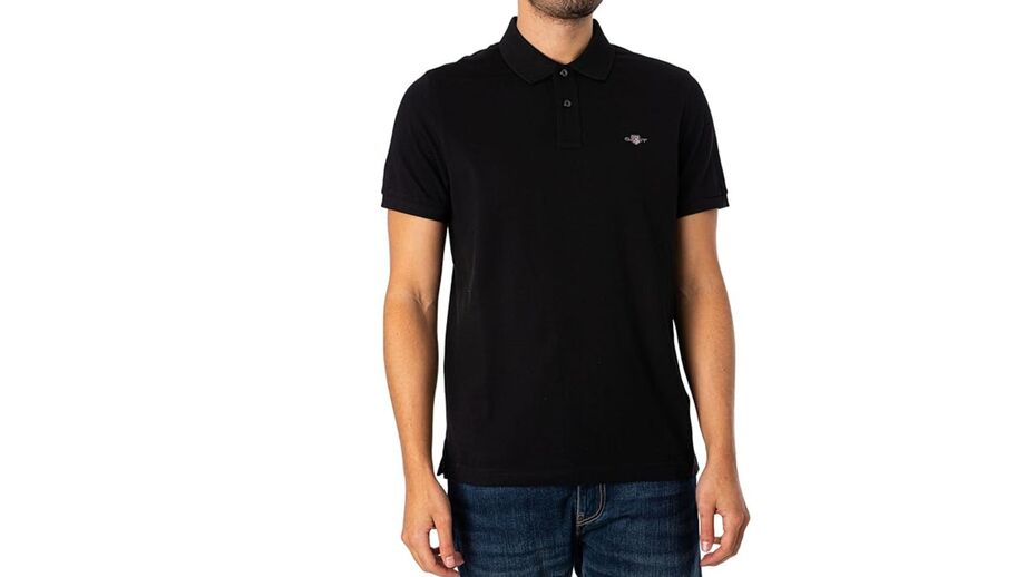 Homem veste polo preta e calças de ganga azuis