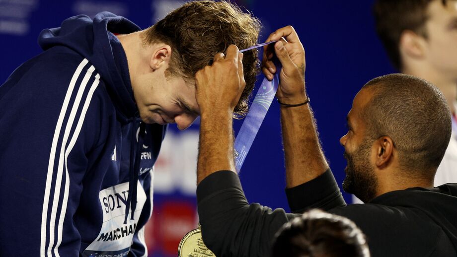 Léon Marchand recebe medalha de ouro das mãos de Tony Parker em Singapura.
