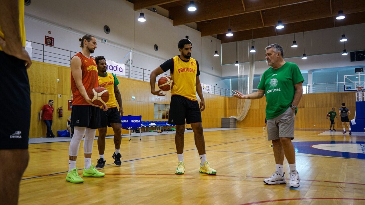 Jogadores de basquetebol portugueses ouvem as indicações do treinador.
