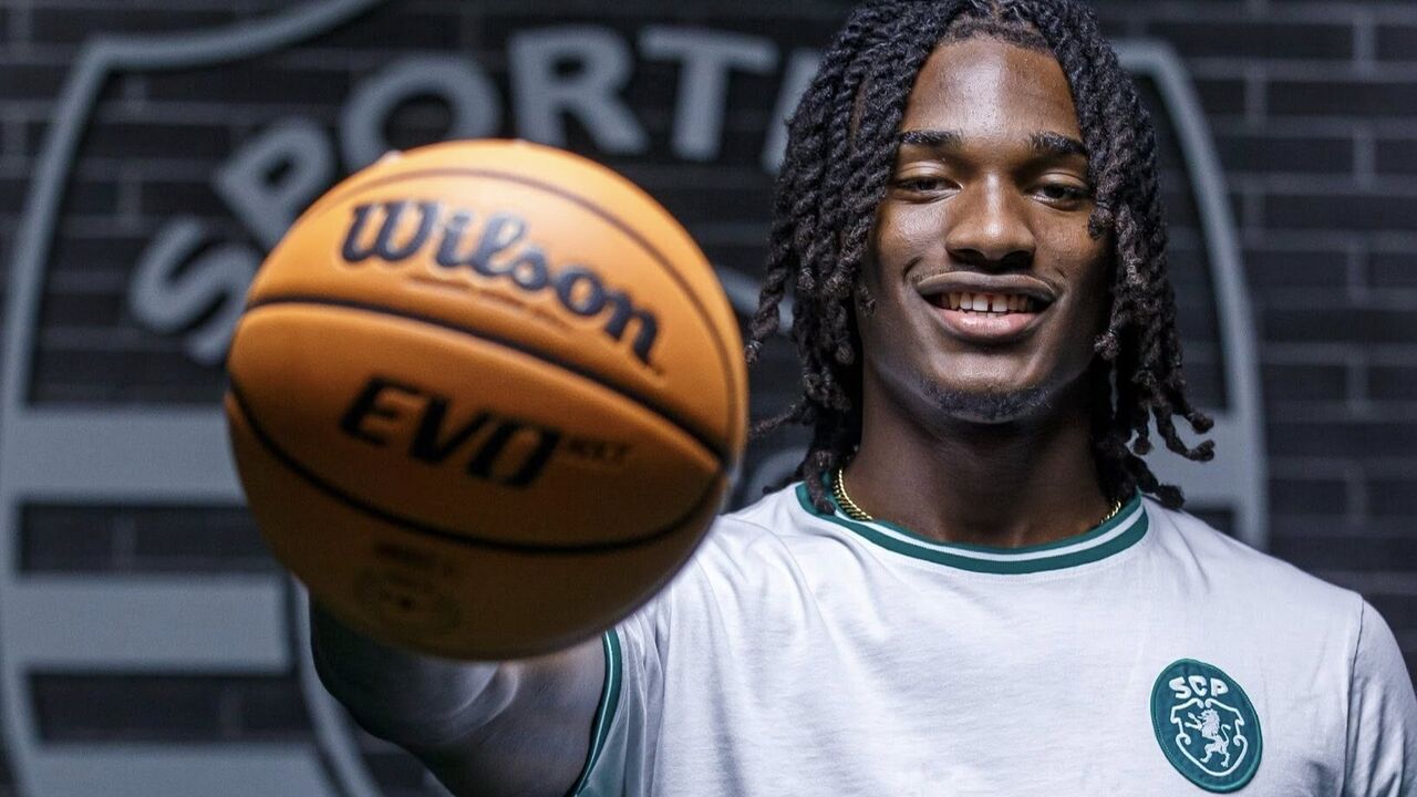 Basquetebolista sorri com a camisola do Sporting e uma bola Wilson na mão