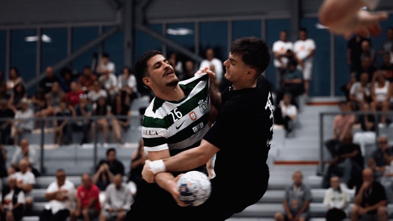 Jogo de andebol com atletas em disputa pela posse da bola.
