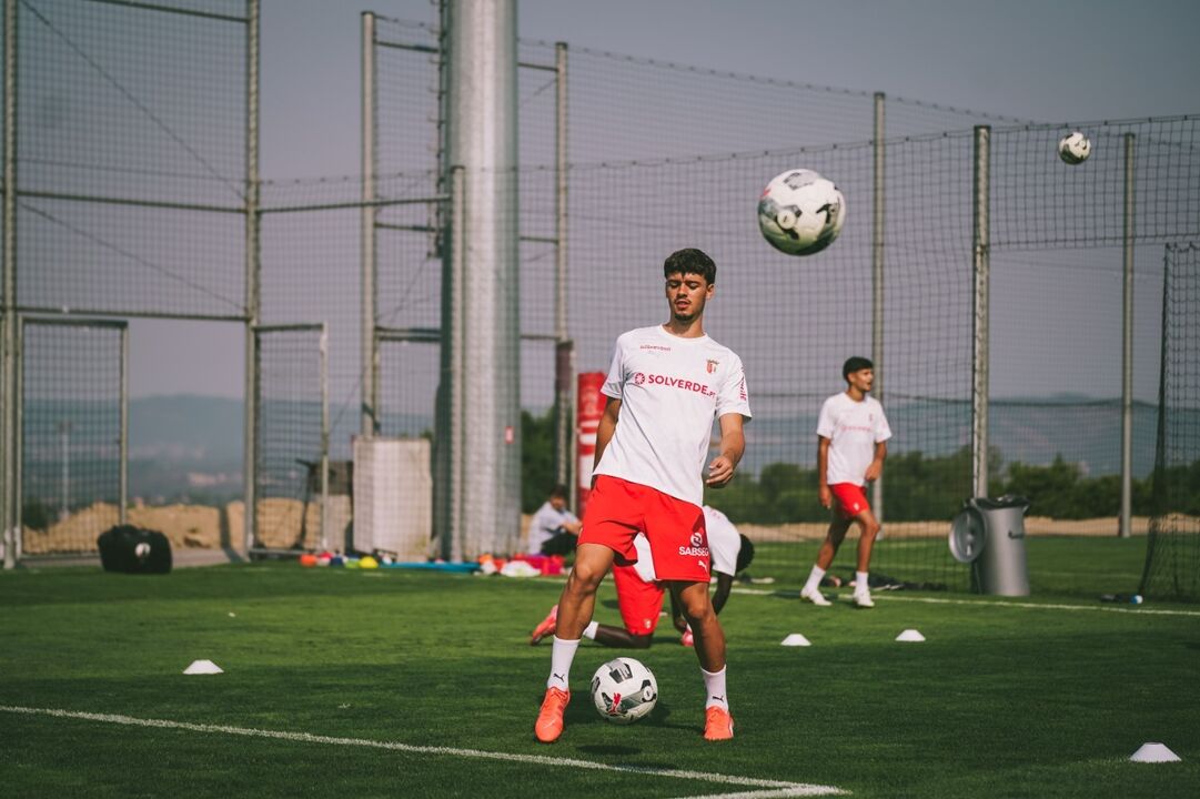 Jogador treina com bola num campo relvado