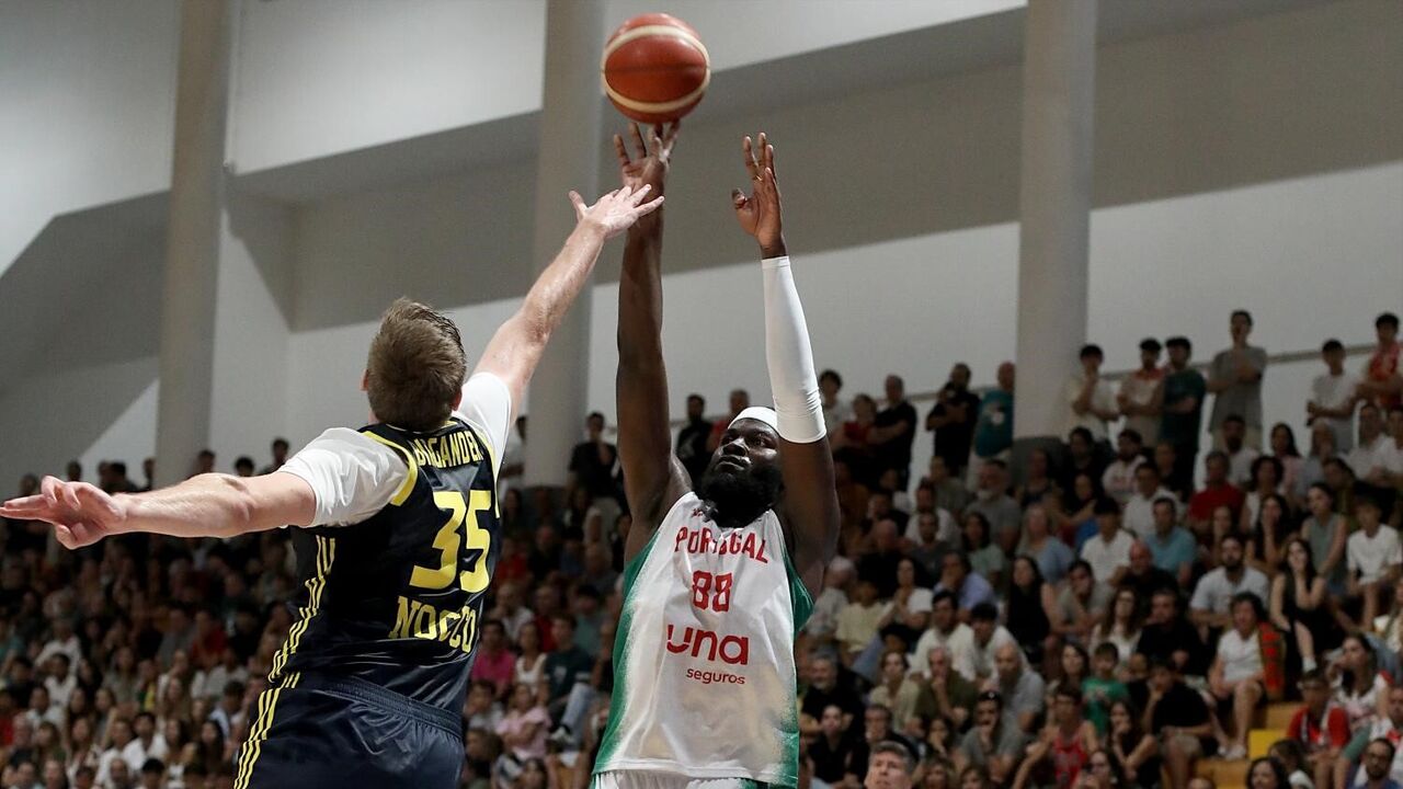 Basquetebolistas em jogo disputam a bola perante o olhar atento do público