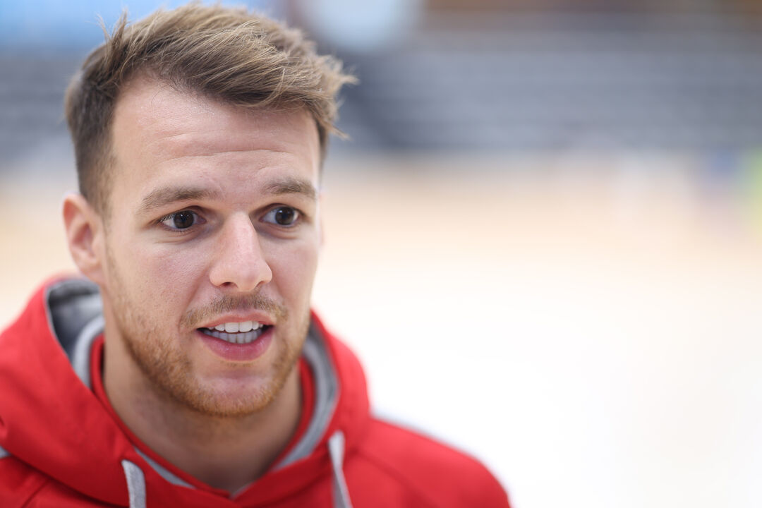 Homem de cabelo loiro e barba ruiva com casaco vermelho