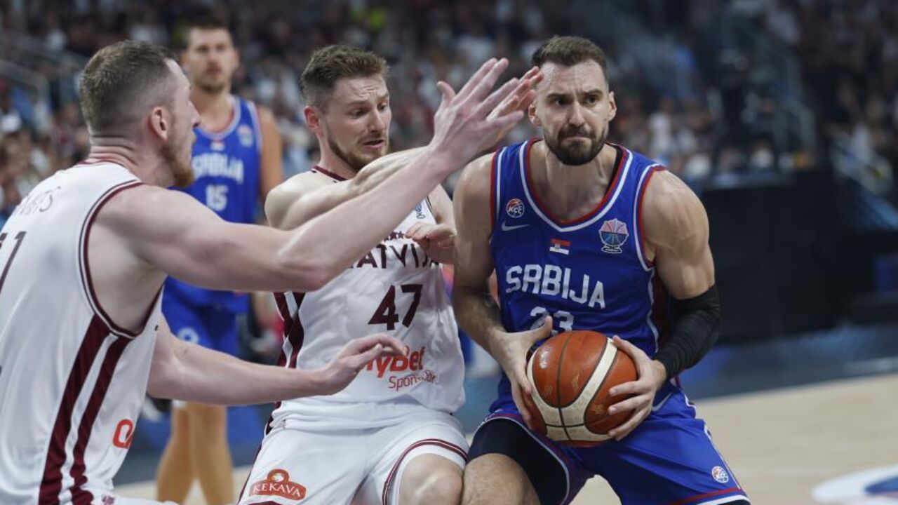 Arturs Kurucs e Rolands Smits, da Letónia, disputam a bola com Marko Guduric, da Sérvia