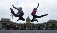 Duas jovens saltam em frente à Catedral de Cazã, em São Petersburgo