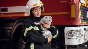Bombeira segura gato perto de carro dos bombeiros
