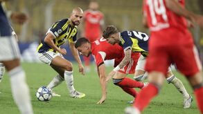 Futebolistas em jogo disputam a posse da bola