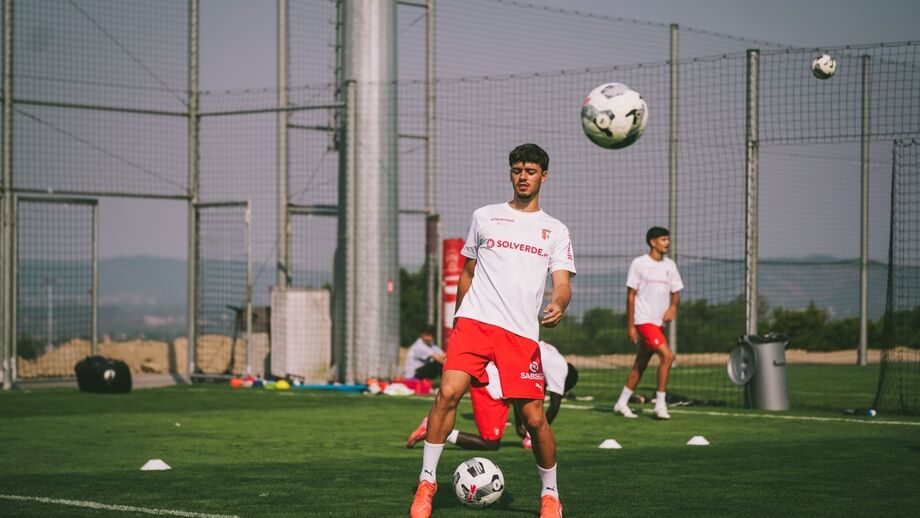 Jogador treina com bola num campo relvado