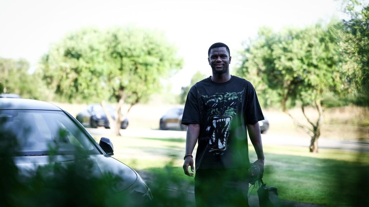 Um homem sorri perto de carros e árvores