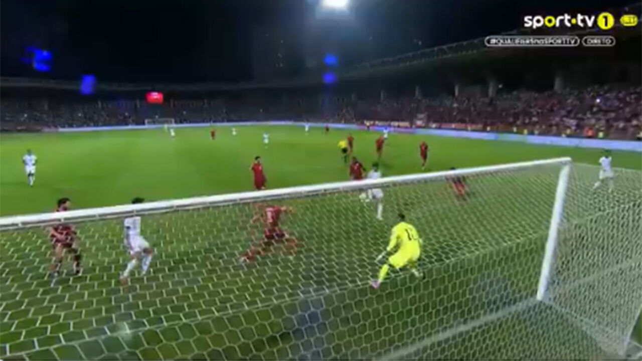 Jogo de futebol com jogadores em campo e o guarda-redes perto da baliza