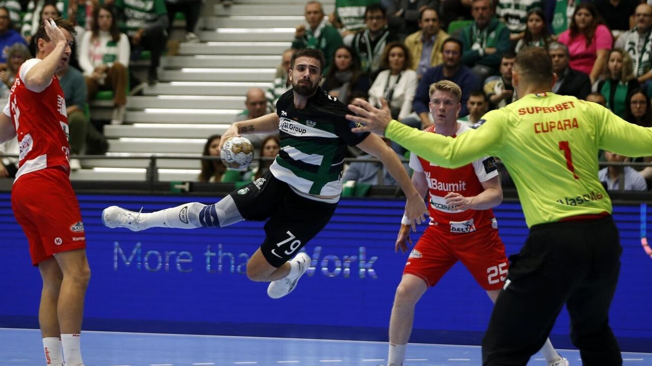 Jogo de andebol com atletas em ação e público nas bancadas