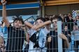 Jovens adeptos apoiam equipa no estádio, com cachecóis e camisolas