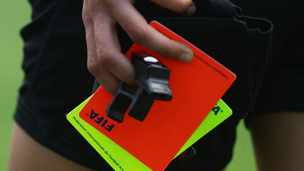 Cartão vermelho e cartão amarelo na mão de um árbitro