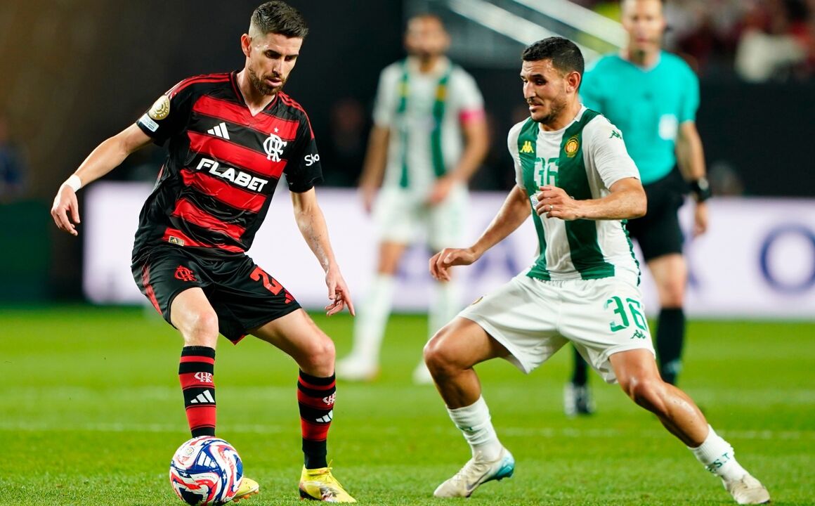 Jogadores em campo durante o jogo de futebol.
