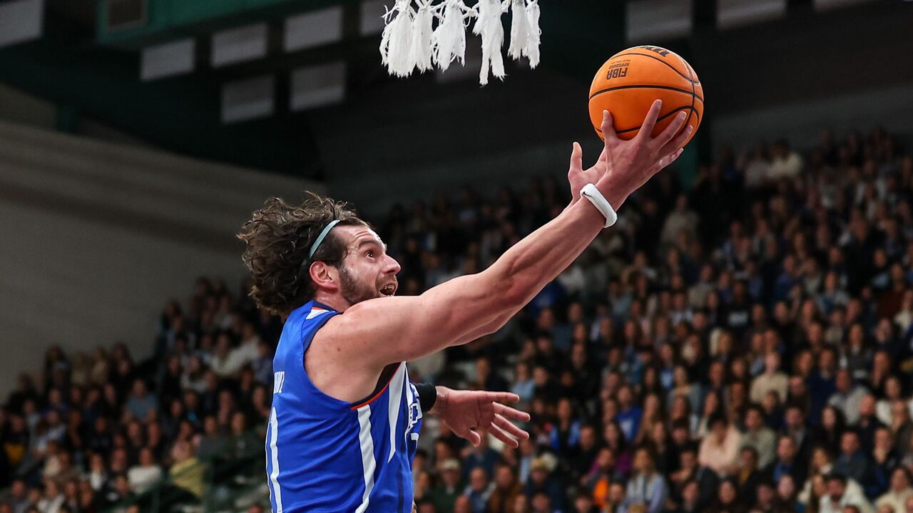 Atleta compete em jogo de basquetebol perante uma plateia cheia