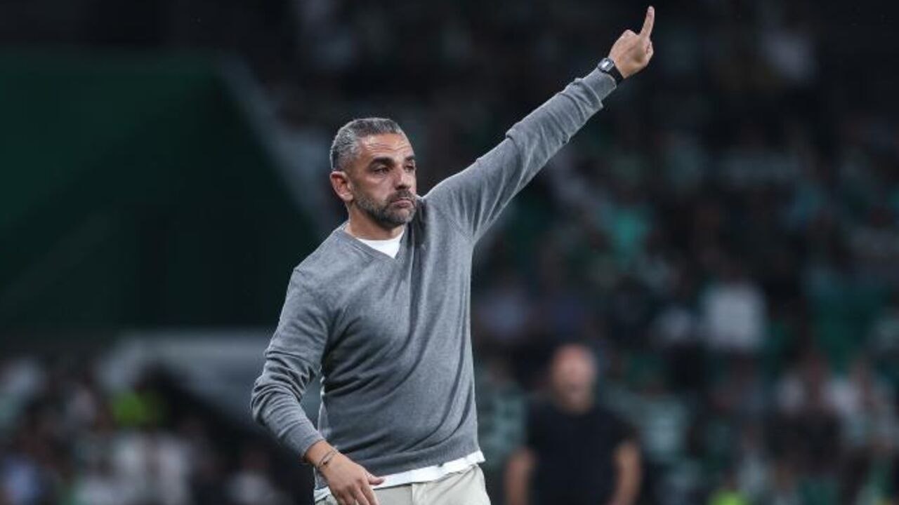 Treinador gesticula durante jogo de futebol num estádio