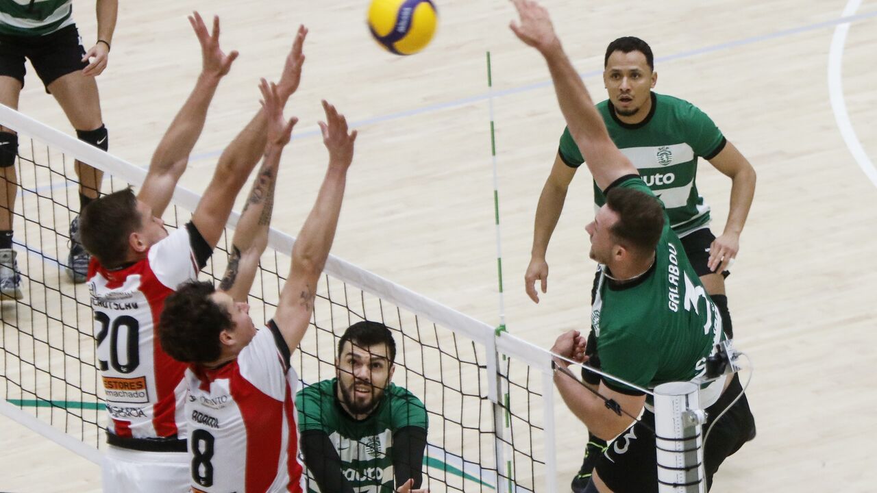 Partida de voleibol com jogadores em ação e bola no ar