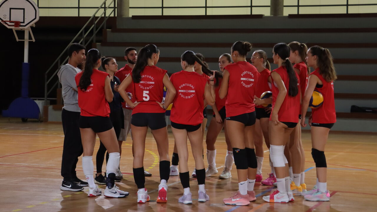 Equipa de voleibol de Portugal reunida em campo com treinadores.
