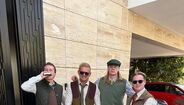 Um grupo de quatro homens posa para uma fotografia com vestuário tradicional