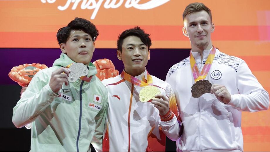 Zou Jingyuan (ao centro) brilha nos Mundiais de ginástica