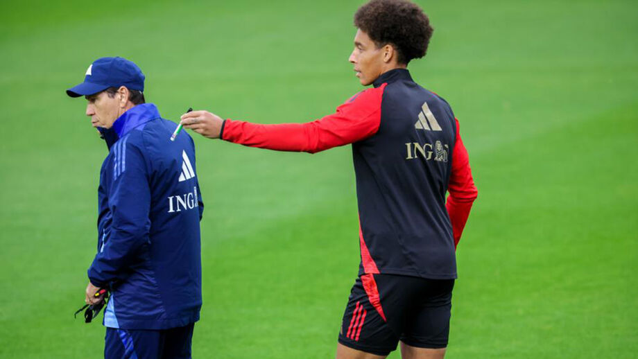 Jogador interage com membro da equipa técnica durante treino.
